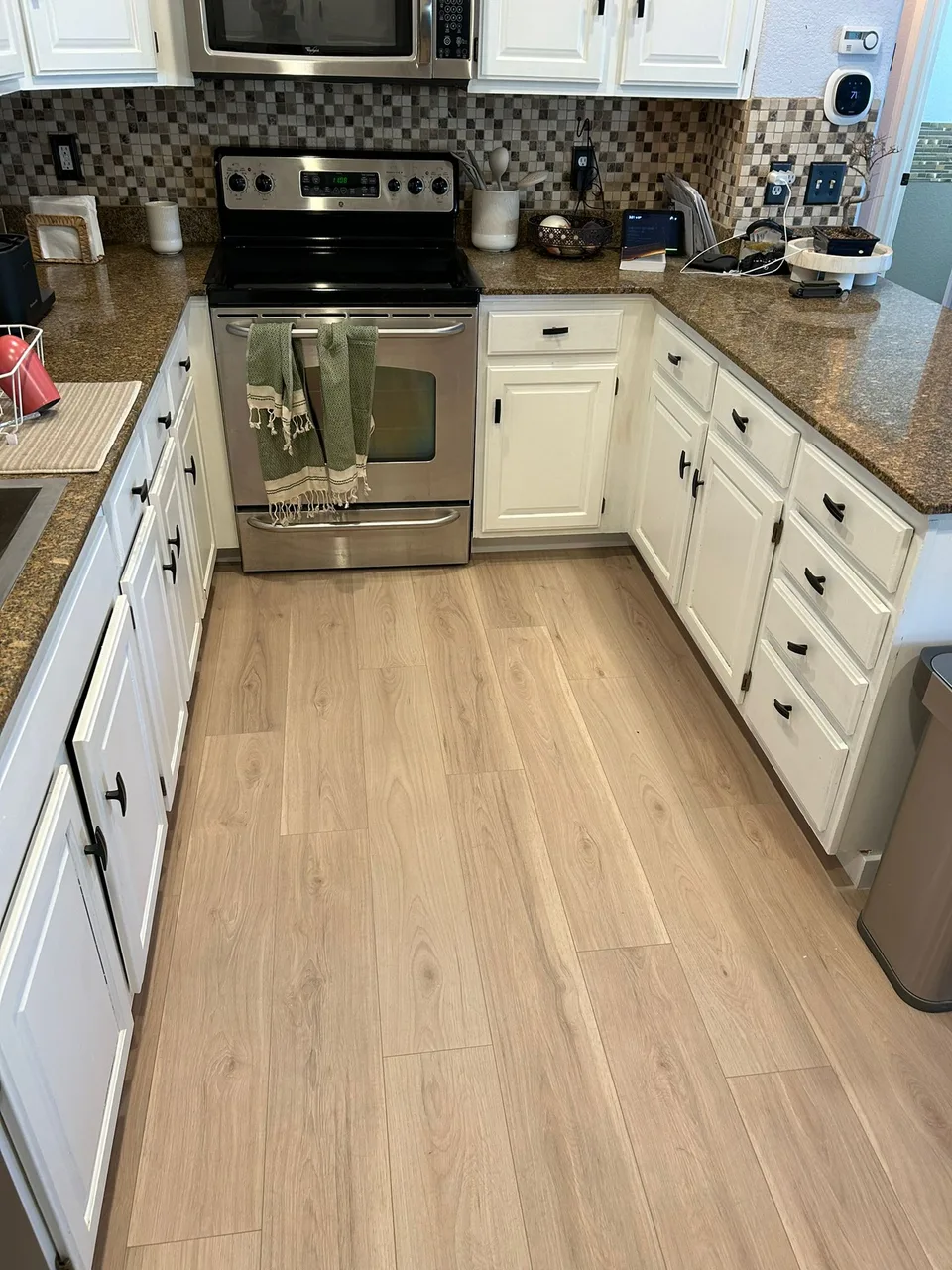 Light wood flooring in a kitchen with white cabinets